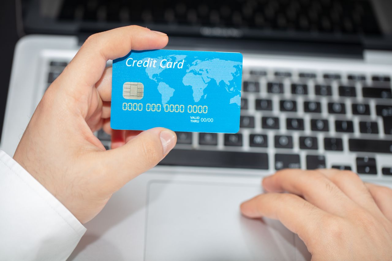 our-journey-01 Person holding credit card near laptop for online shopping, emphasizing secure online transactions.