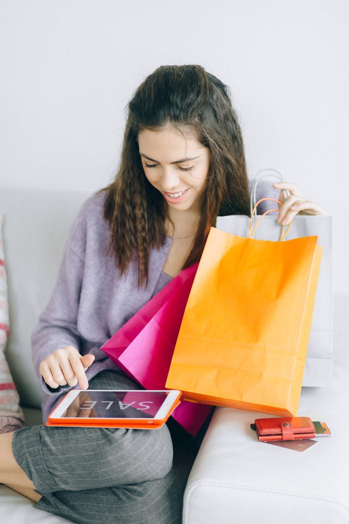 Young woman shopping online with a tablet and colorful shopping bags at home.